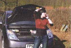 C1 Advanced Speaking - Young woman in a red top and jeans making a phone call in front of a car that has its bonnet up