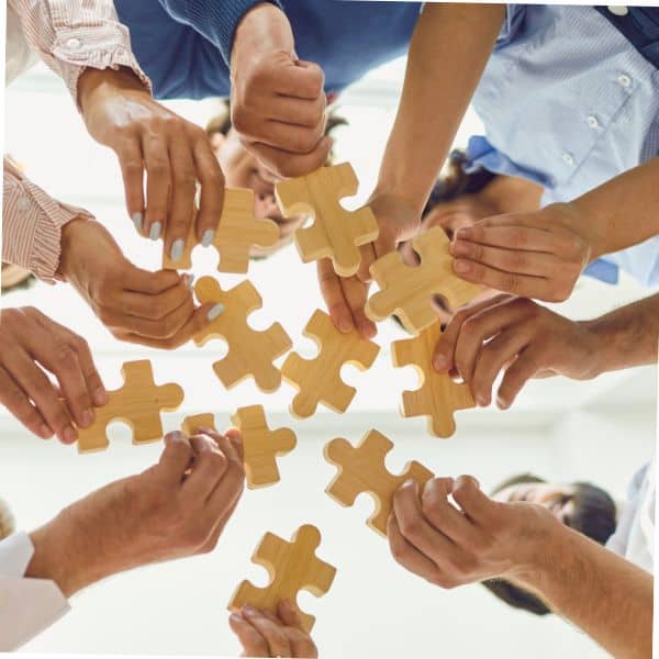Looking up at people holding parts of a jigsaw puzzle