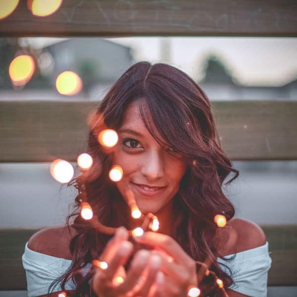 A smiling dark-haired woman with sparkles coming from her cupped hands - Write a C1 Advanced Part 1 Essay