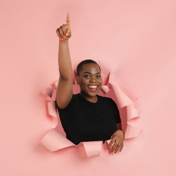Young smiling woman with short hair and arm raised bursting through a pink background - C1 Advanced Review writing made easy