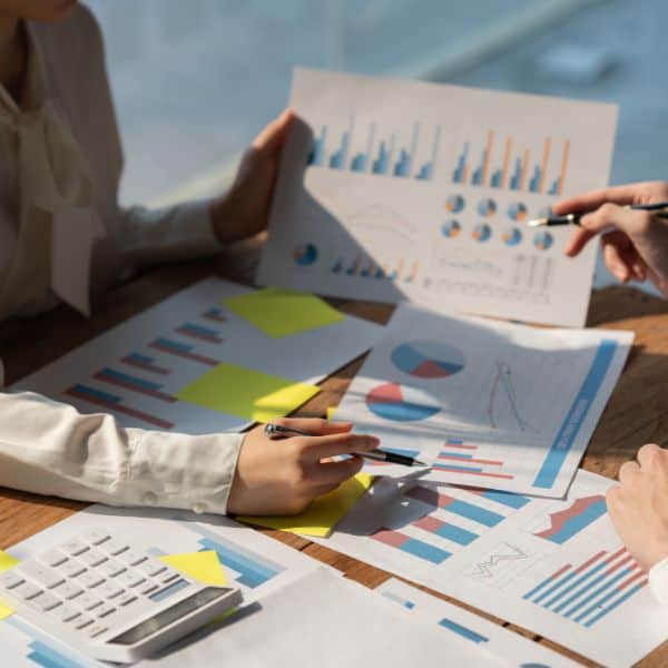 Someone holding sheets of various charts at a desk - How to write An IELTS Academic Task 1 Essay