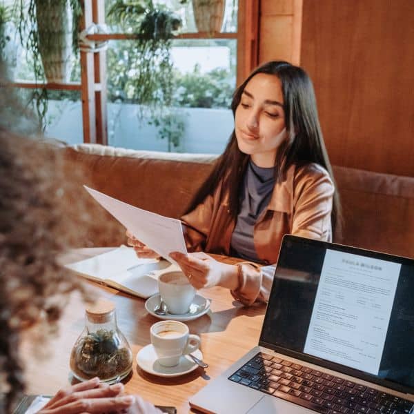 Woman with long black hair looking over a piece of paper, sitting at a desk - IELTS General Training Writing Task 1 Questions