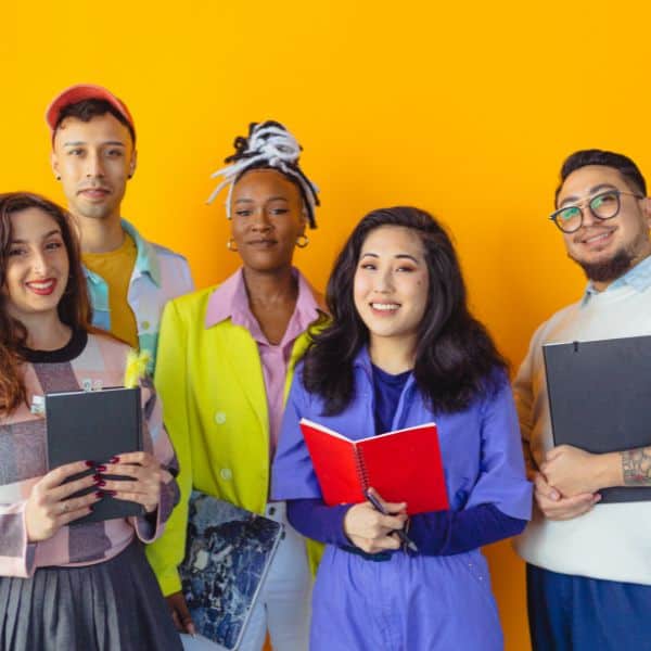 Group of smiling young men and women with a yellow background - C1 Advanced Template Sentences for Writing Part 1