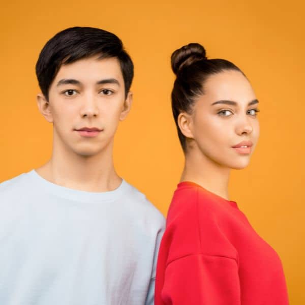 A young dark-haired man in a white T-shirt and a young woman with her dark hair in a bun in a red T-shirt against an orange background - IELTS Speaking Part 2 - Phrases & Vocabulary
